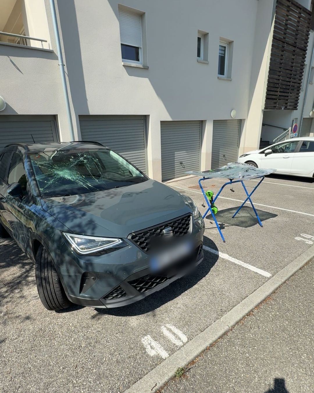 Seat Arona au pare-brise éclaté, pare-brise neuf posé sur un chevalet à côté